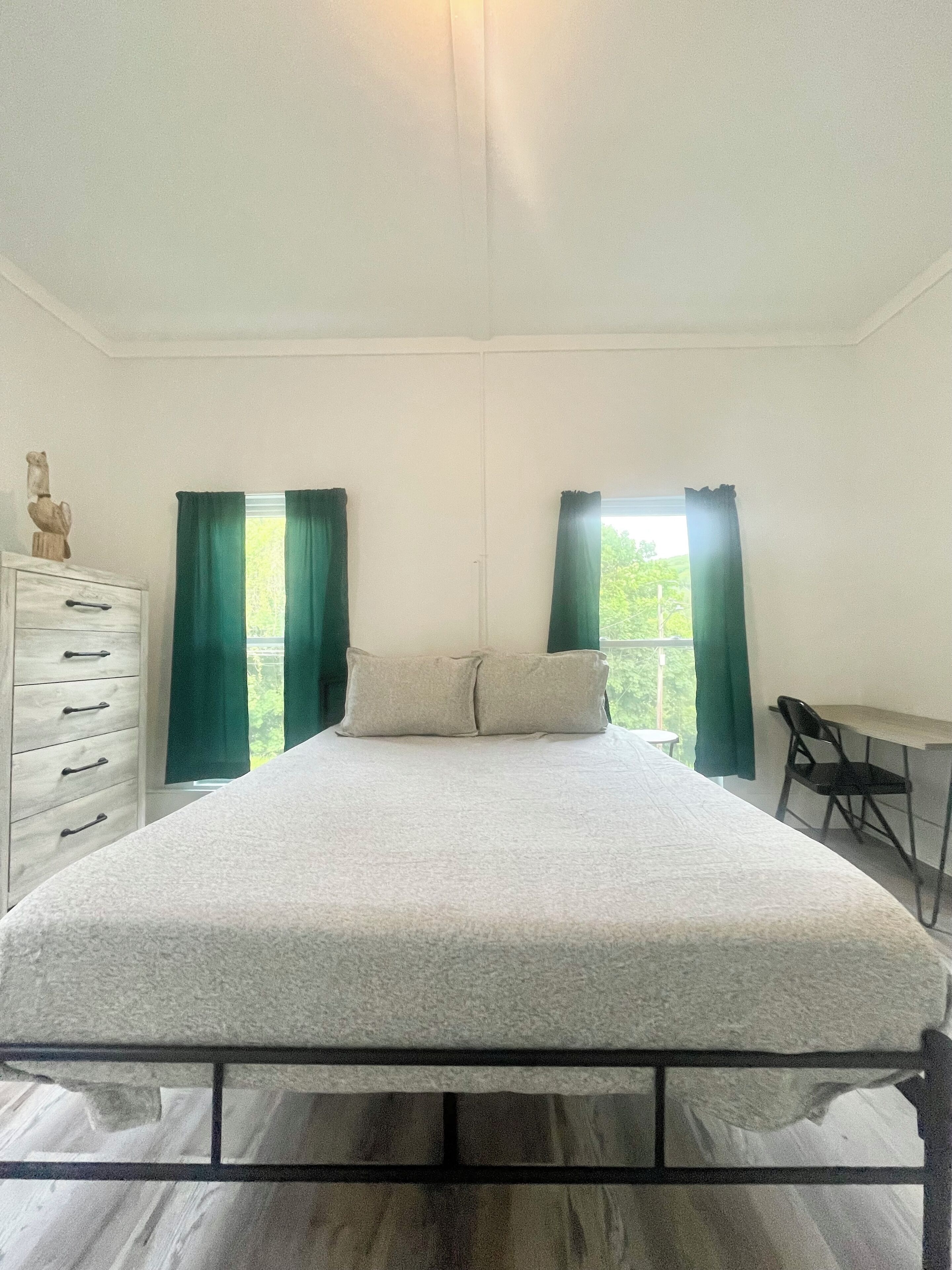 A bedroom with a bed, a dresser, a desk, and a chair.