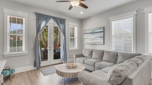 A living room with a beige sectional sofa, a round coffee table, and a ceiling fan.