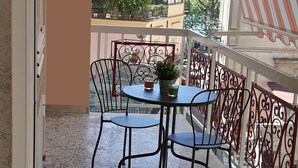 A balcony with a table and chairs, a potted plant, and a view of buildings and trees. - Sapore di Mare Holidays (Maiori)