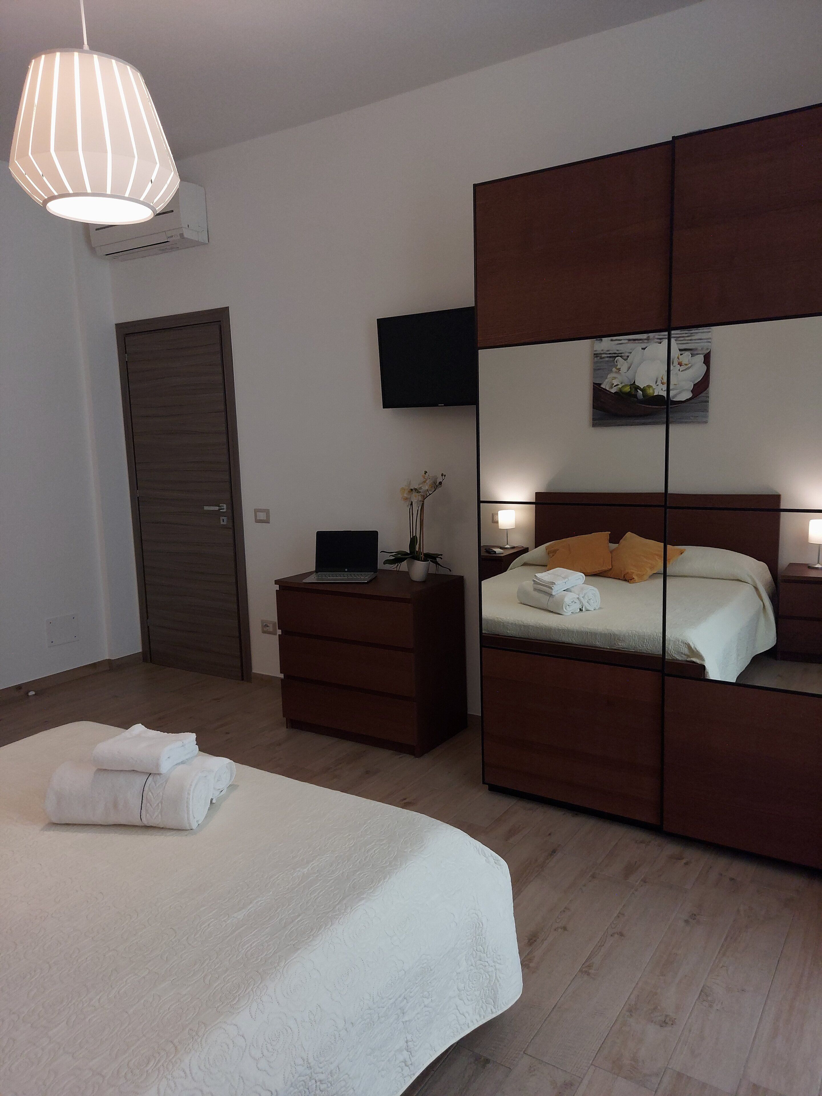 Une chambre à coucher avec un lit, une commode, une télévision et un miroir.