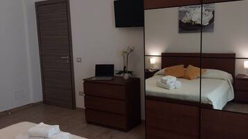 Une chambre à coucher avec un lit, une commode, une télévision et un miroir.