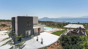 Una casa moderna con piscina, zona de estar cubierta al aire libre y vista al mar.