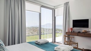 Una habitación de hotel con cama, escritorio y televisor, y vistas a la ciudad y las montañas.
