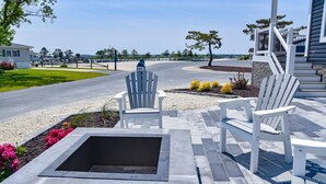 A patio area with Adirondack chairs, a fire pit, and a stop sign in the background. - Family fun-beach, marina, pools, pet friendly! (Long Neck)