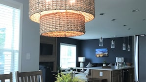 A dining area with a round wooden table, a woven pendant light, and a potted plant. - Large home-marina, beach, pools (Long Neck)