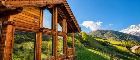 A wooden cabin with a balcony overlooking a mountainous landscape.