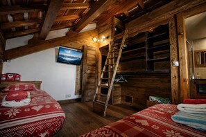 A rustic wooden room with a loft bed, a television, and a ladder. - Large chalet in Vars for 19 people—indoor pool, spa, movie theater, mountain views (Vars)