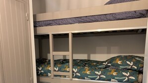 Un lit superposé à trois niveaux, chaque niveau étant doté d’une couverture à motifs.