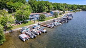 A marina with boats docked, a house with a dock, and a forested area in the background. - 3 Separate room with private balconies with stunning lake views (Fife Lake)