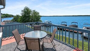 A balcony with a table and chairs overlooking a lake, with boats docked nearby. - 3 Separate room with private balconies with stunning lake views (Fife Lake)