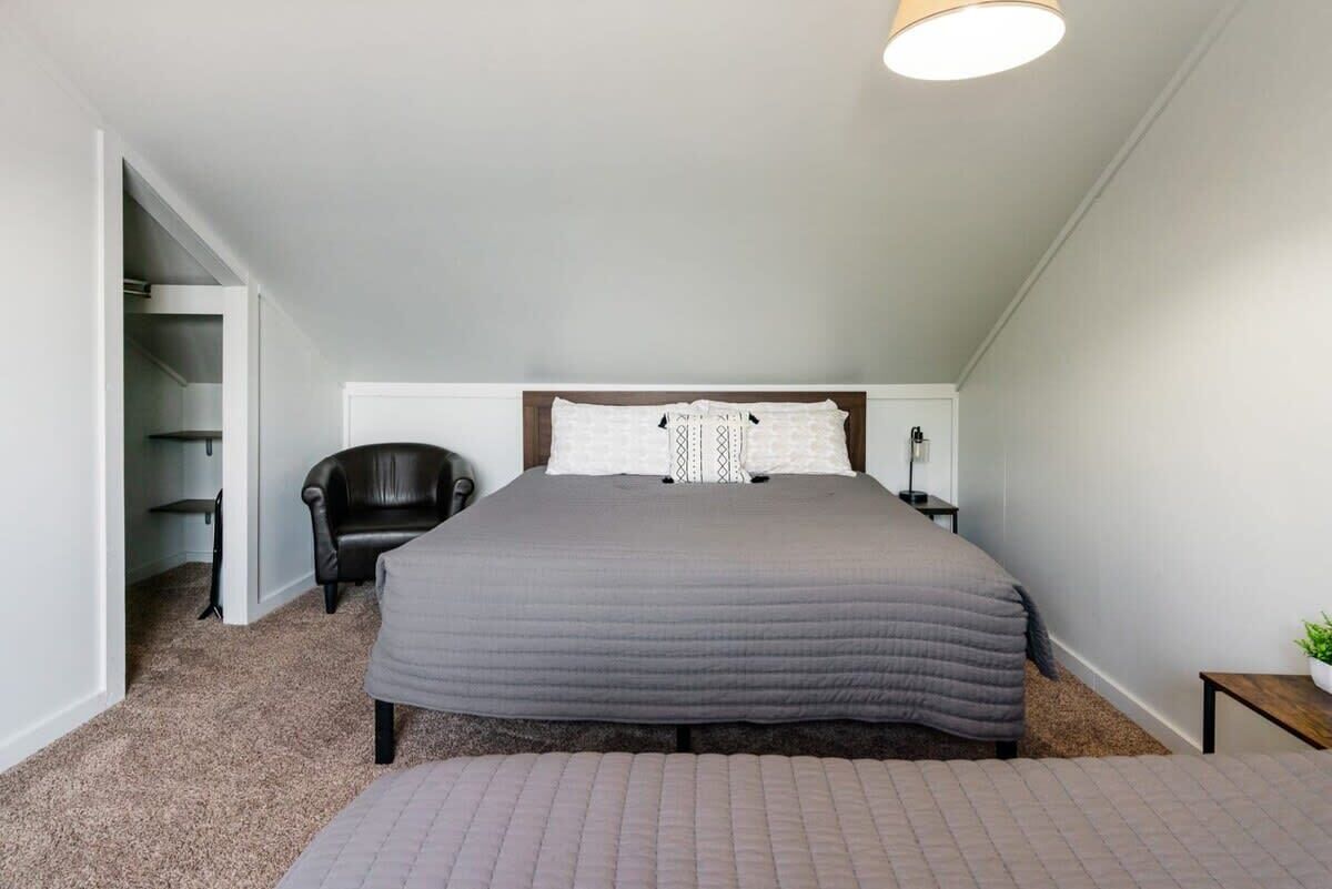 Ein Schlafzimmer mit einem großen Bett, einem Sessel, einem Nachttisch und einem Beistelltisch.