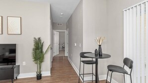 A modern living room with a flat-screen TV, a coffee table, two chairs, and a potted plant. - Relax in Comfort! 2BR Condo Close to Grand Rapids (Wyoming)