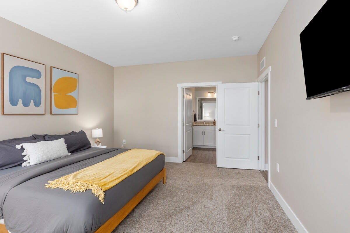 A bedroom with a bed, a TV, and artwork on the wall.