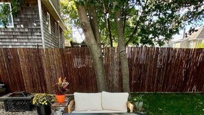 An outdoor patio with a wooden bench, a small table, and a potted plant.