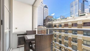 A balcony with wicker furniture and a view of adjacent buildings.