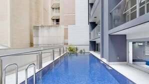 An indoor swimming pool with a clear view of the surrounding building's architecture, including balconies and a glass facade.