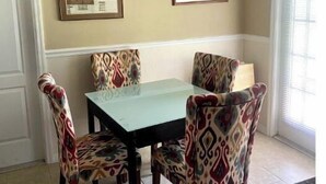 Un coin repas comprenant une table et quatre chaises à motifs, un lustre et deux tableaux encadrés accrochés au mur.