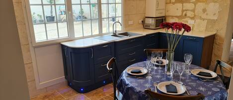 A dining area with a table set for four, a sink, and cabinets.