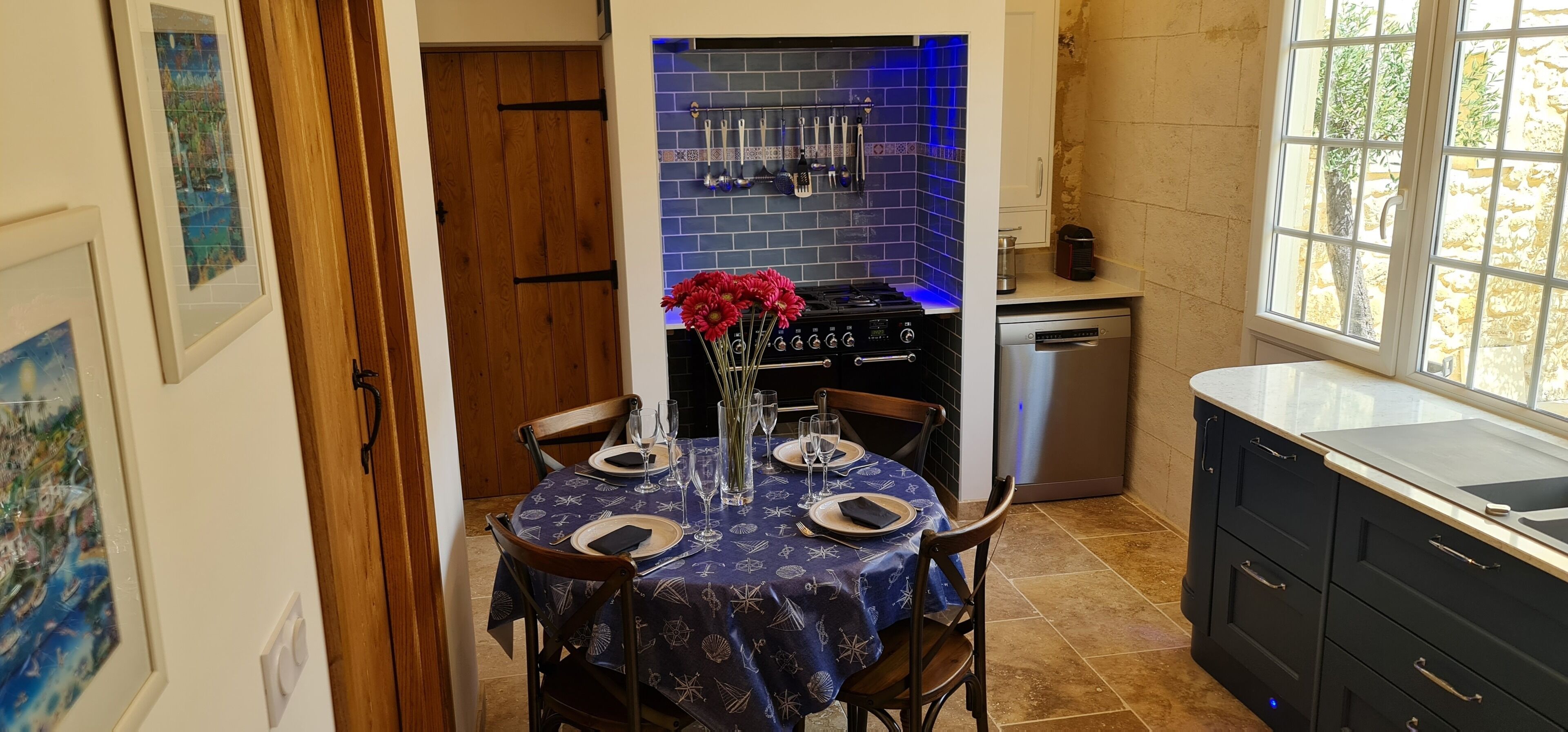 A kitchen with a dining area, featuring a stove, sink, and cabinets.