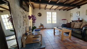 A living room with a wooden coffee table, a black leather sofa, and a potted orchid. - Luxury 5* cottage with own private heated pool - Sleep 4 (Villegouge)