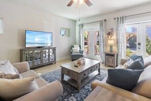 A living room with a television, sofa, coffee table, and a view of the outdoors through a glass door.