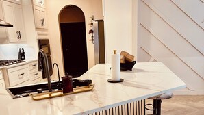 Una cocina moderna con una isla central, paneles de madera y un patrón de suelo tipo espiga.