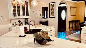 Una cocina moderna con encimera de mármol, luces colgantes y una isla central con asientos.