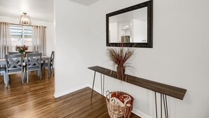 Un coin repas avec une table et des chaises en bois, un miroir au mur et une plante décorative.