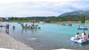 A lake with boats, people, and a mountainous backdrop.