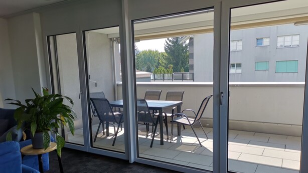 A room with a sliding glass door leading to an outdoor patio area with a table and chairs. - Ferienwohnung Hirschen (Gossau)