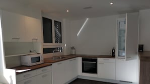A modern kitchen with white cabinets, a microwave, a sink, and a dishwasher. - Ferienwohnung Hirschen (Gossau)
