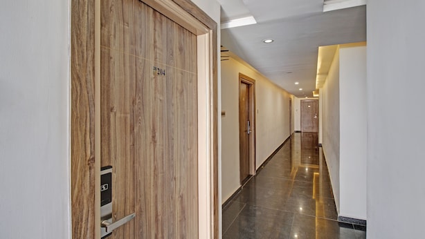 A modern hotel corridor with wooden doors, a polished floor, and recessed lighting.