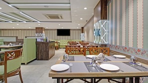 A restaurant with a long counter, multiple tables with chairs, and a bar area.