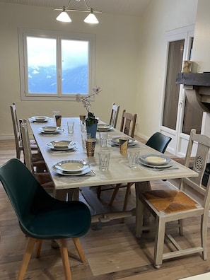 Ein Esszimmer mit einem großen Tisch, gedeckt für sechs Personen, umgeben von Holzstühlen mit Sitzpolstern.