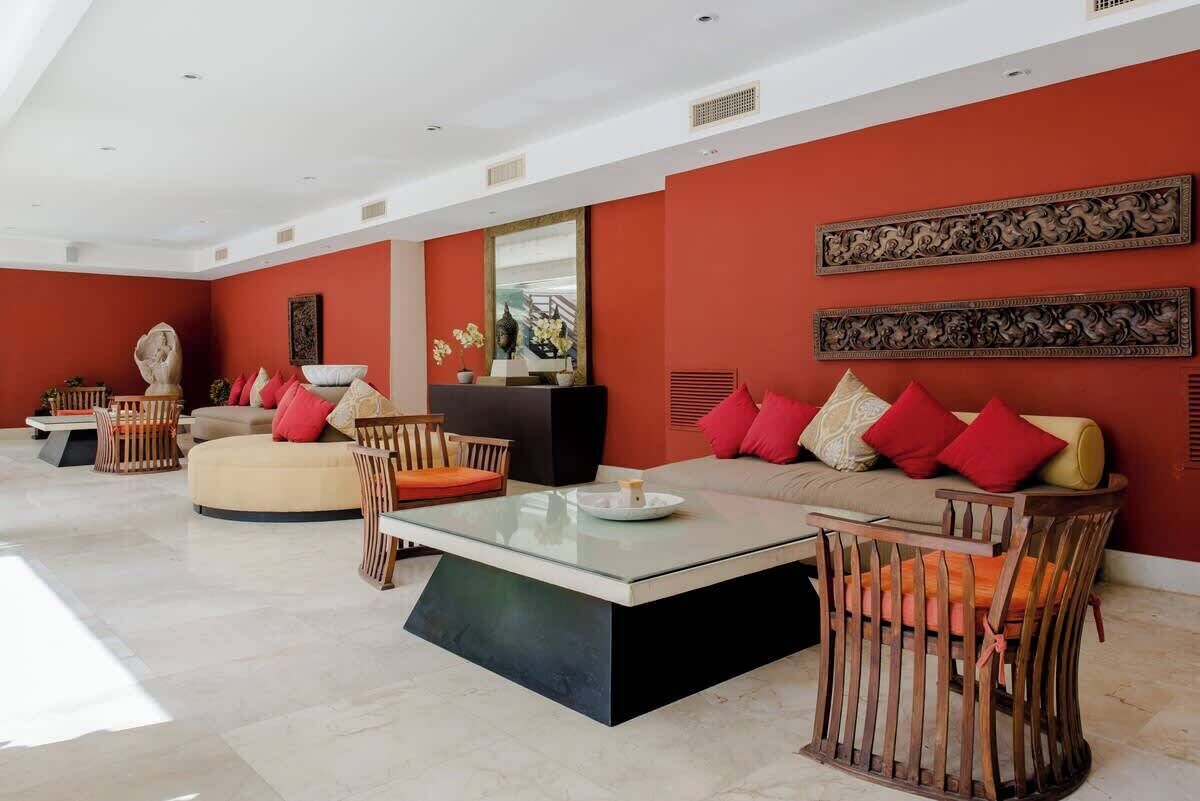 A modern living room with a red accent wall, a glass coffee table, and a sofa with red cushions.