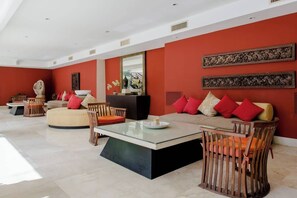 Ein modernes Wohnzimmer mit roter Akzentwand, einem Glastisch und einer Couch mit roten Kissen.