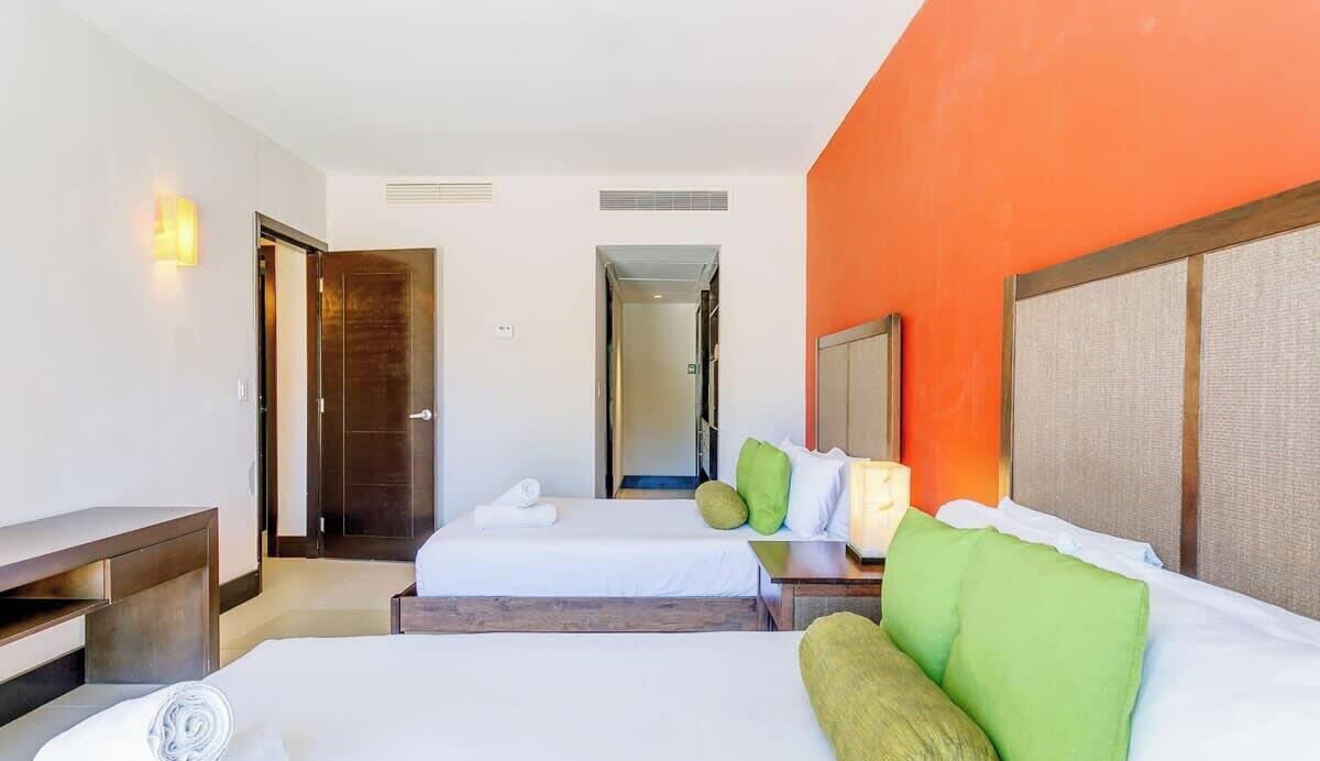 A hotel room with two beds, a desk, and a mirror.