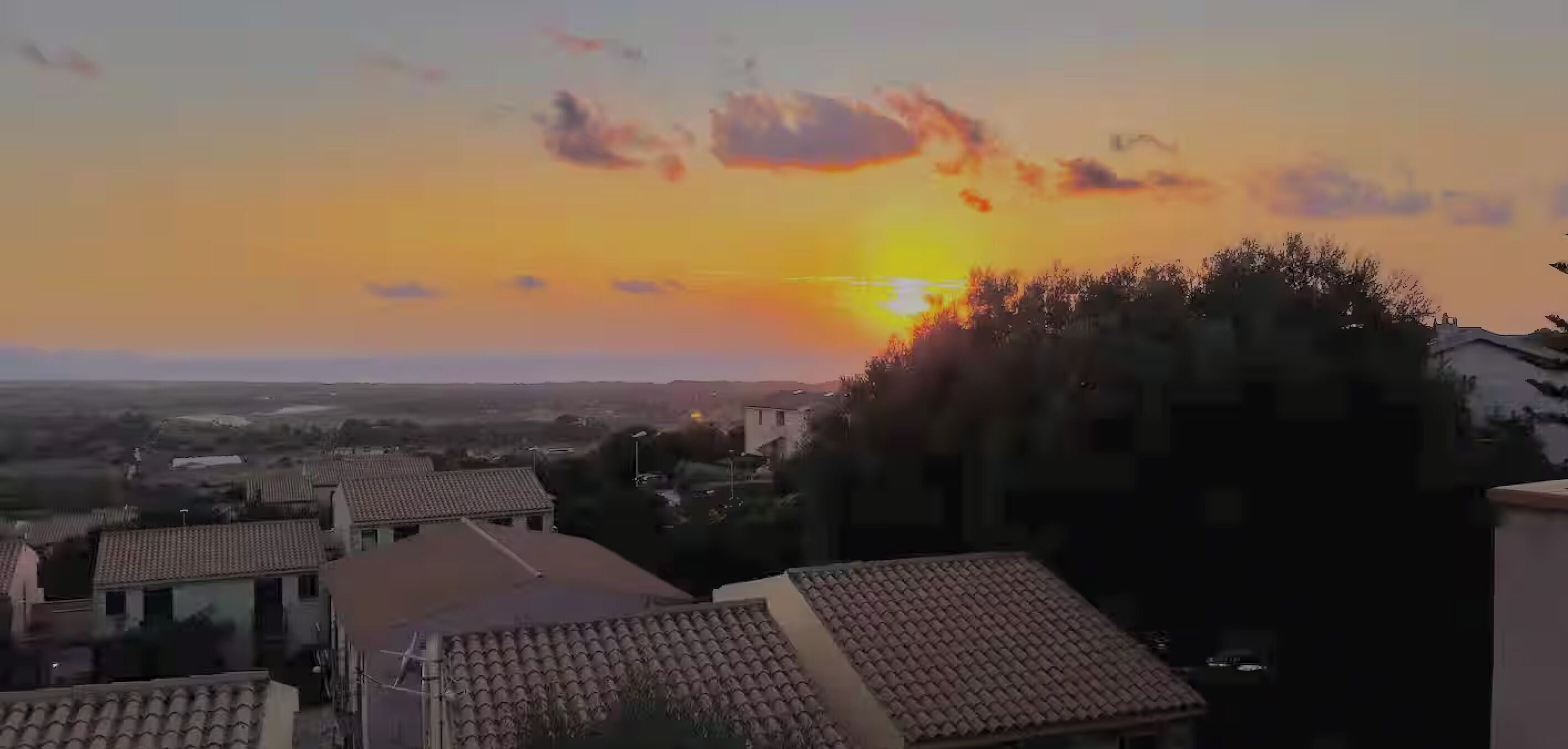 Tramonto su una zona residenziale con case e cielo sereno.