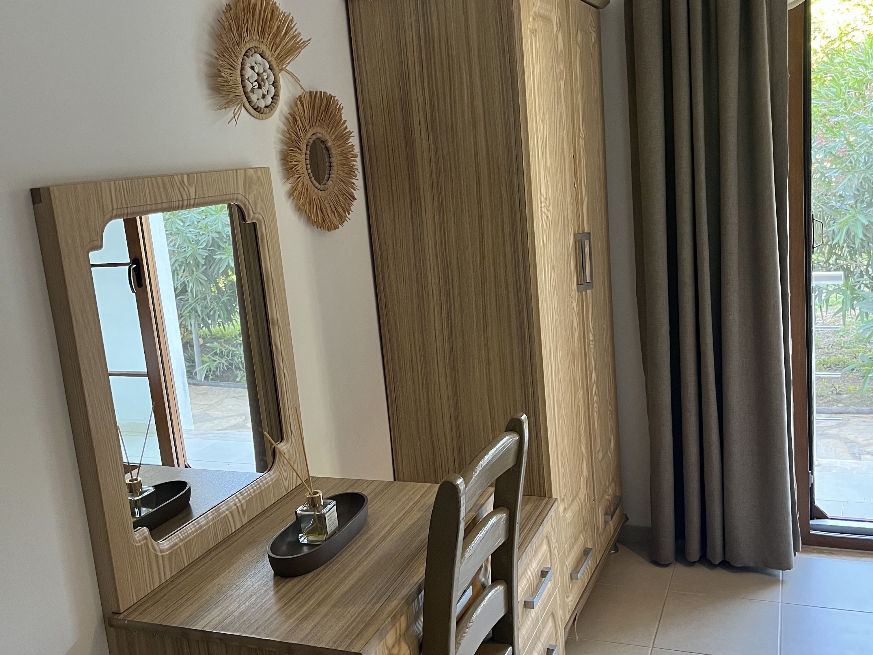 Una habitación con tocador de madera, espejo, armario y vistas a zonas verdes.