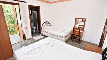 Un dormitorio con cama, una silla, una mesita, un espejo y la puerta del baño.