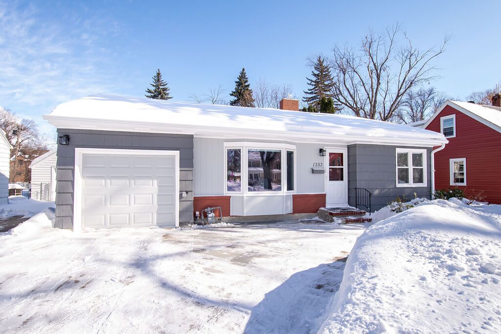 A two-story house with a garage, a front porch, and a snow-covered driveway.