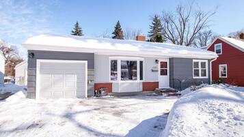 A two-story house with a garage, a front porch, and a snow-covered driveway.
