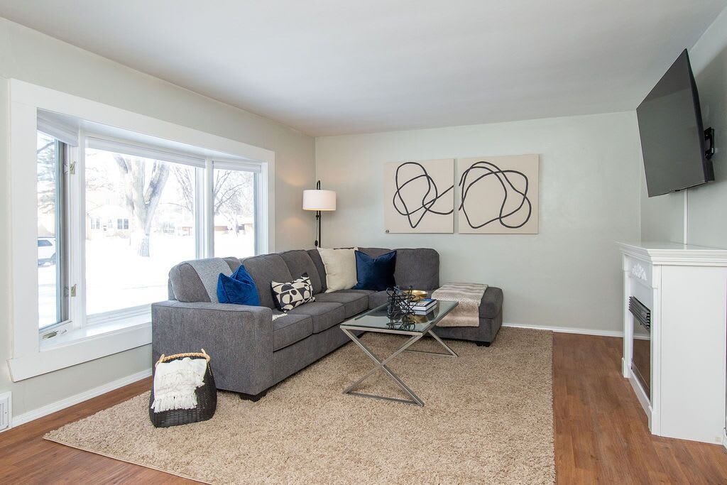 A modern living room with a grey sectional sofa, a glass coffee table, and abstract wall art.