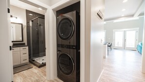 Een moderne wasruimte met een voorlader wasmachine en droger, een inloopdouche en een kleine kitchenette.