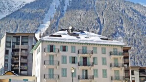 Ein mehrstöckiges Gebäude mit Balkonen, im Hintergrund ein schneebedeckter Berg und ein klarer Himmel.