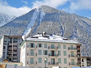 A multi-story building with balconies, a snow-covered mountain in the background, and a clear sky. - Le Pavillon by Interhome (Chamonix)