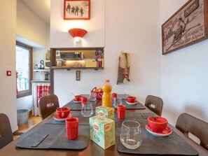 A dining area with a table set for four, equipped with red cups, a bottle of juice, and a box of Lipton tea. - Le Pavillon by Interhome (Chamonix)