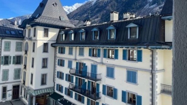Ein mehrstöckiges Hotel im klassischen europäischen Stil mit Balkonen und einem Blick auf die Berge.