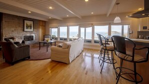 A spacious living room with a fireplace, a sofa, and a view of the sea. - Spectacular Ocean Front Views "Sea Star Escape" A (Brookings)