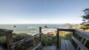 A wooden staircase leading to a viewing platform overlooking the ocean with rocky outcrops and a clear sky. - Spectacular Ocean Front Views "Sea Star Escape" A (Brookings)